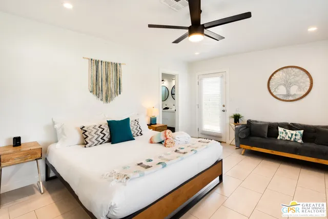 a bedroom with a bed a couch and a chandelier