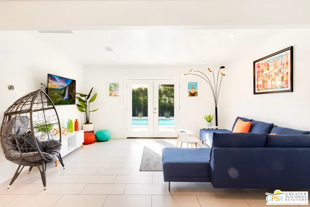 a living room with furniture a flat screen tv and a floor to ceiling window