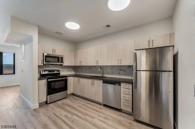 a kitchen with stainless steel appliances granite countertop a refrigerator a stove a sink and a microwave