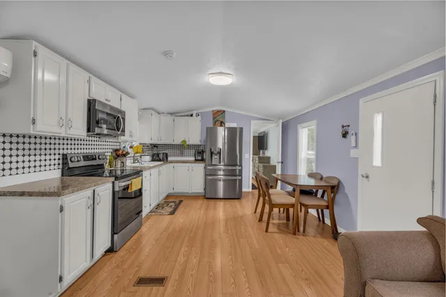 a kitchen with granite countertop stainless steel appliances refrigerator cabinets dining table and chairs