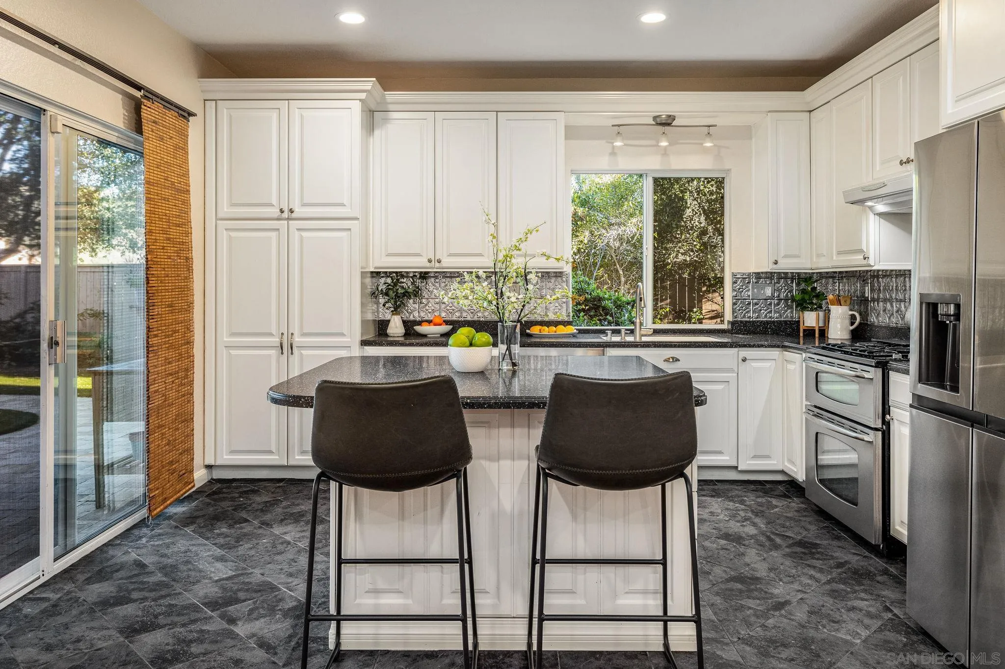 5462 Senegal Street Oceanside, CA 92057 - Photo 11 of 47 a kitchen with stainless steel appliances granite countertop a stove a refrigerator a sink and white cabinets with wooden floor