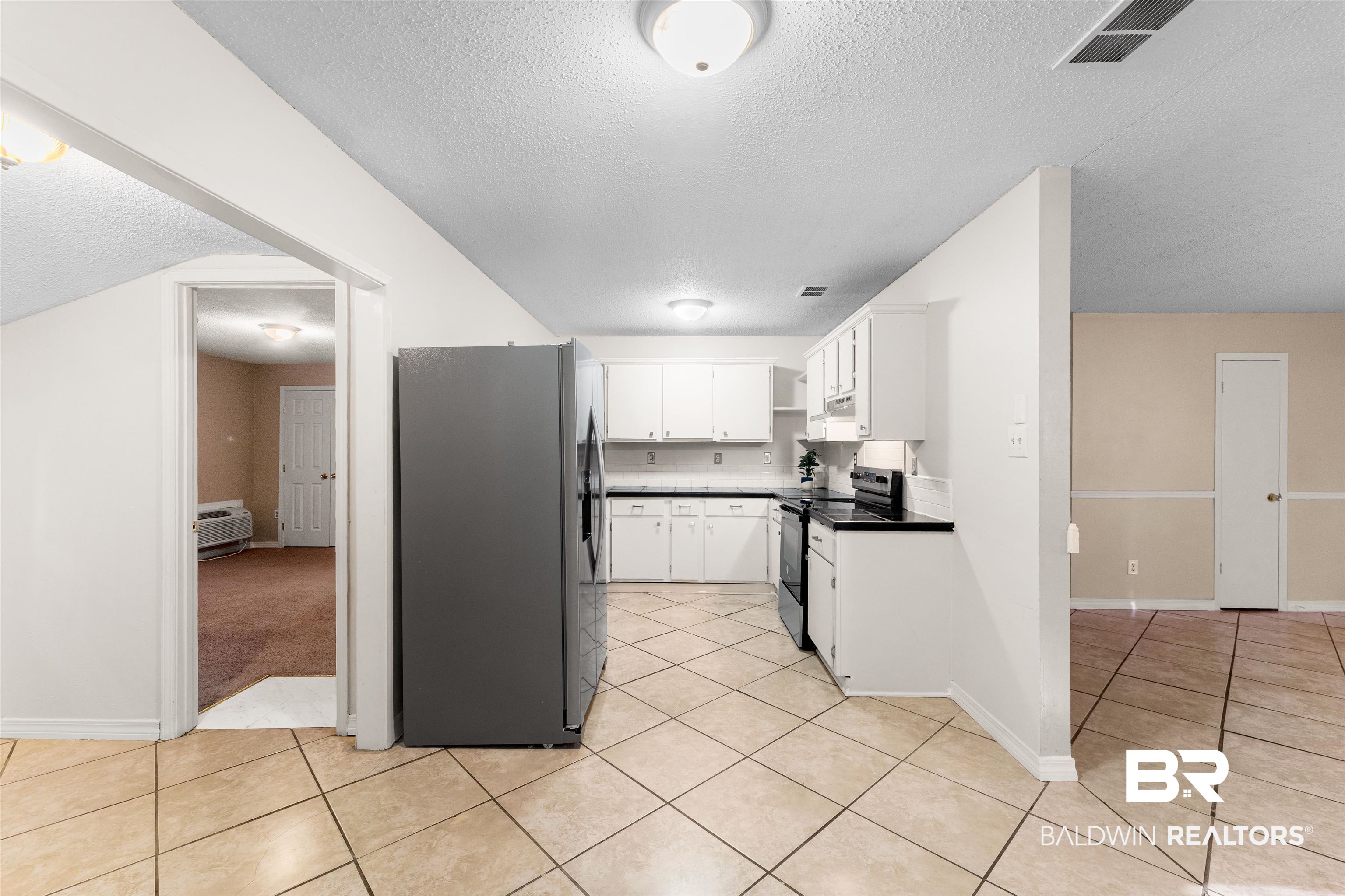 5551 Springer Court Theodore, AL 36582 - Photo 3 of 37 Kitchen featuring white cabinets, stainless steel fridge, electric range, a textured ceiling, and light tile patterned floors