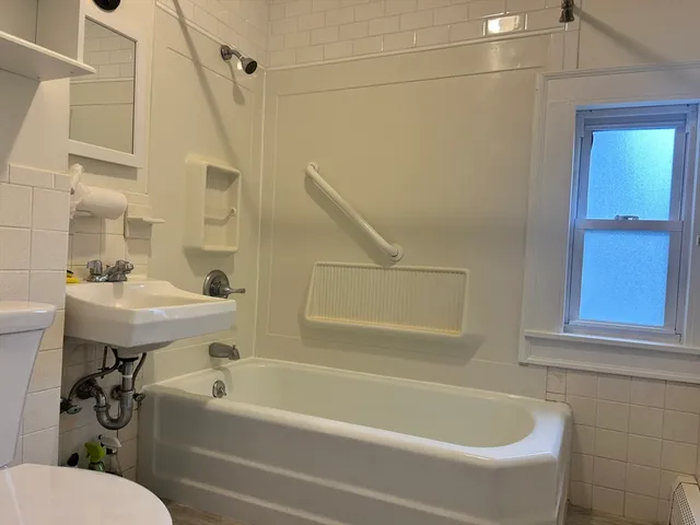 a white bath tub sitting next to a white sink and a mirror