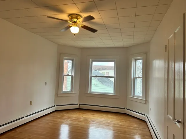 a view of an empty room with window and wooden floor
