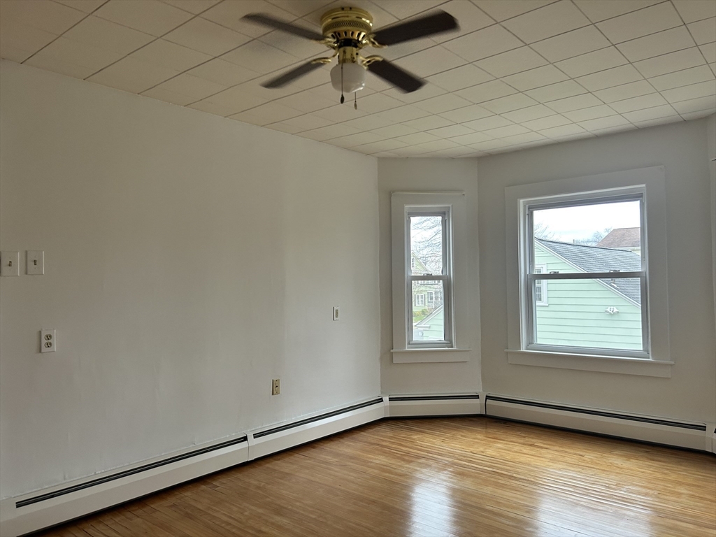 17 Lincoln Street, Unit 2 Greenfield, MA 01301 - Photo 7 of 26 an empty room with wooden floor chandelier fan and windows