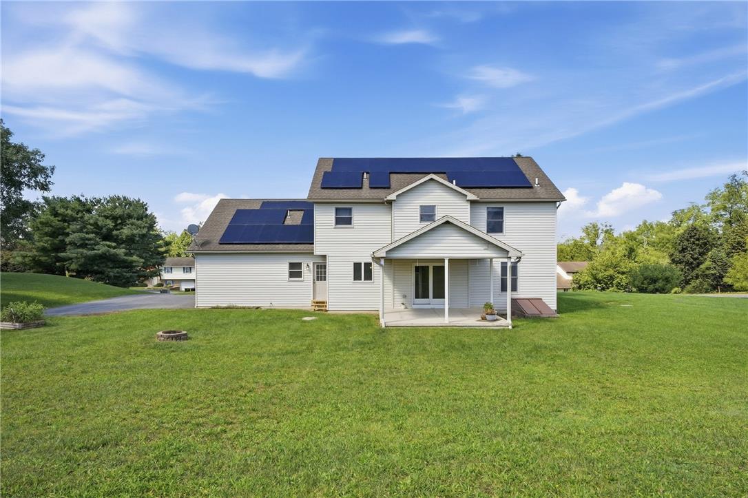 590 Fehr Road Nazareth, PA 18064 - Photo 65 of 79 A spacious grassy lawn stretches behind this multi-level home featuring solar panels and a covered patio.