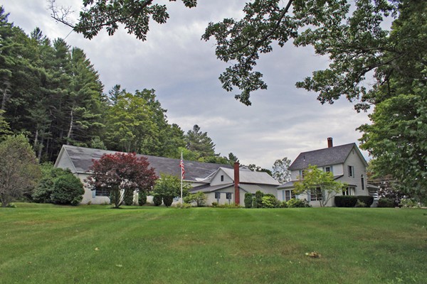 a view of a big house with a big yard and large trees