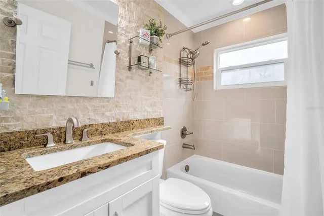 a bathroom with a granite countertop sink a toilet and bathtub