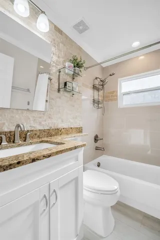 a bathroom with a granite countertop toilet sink and bathtub