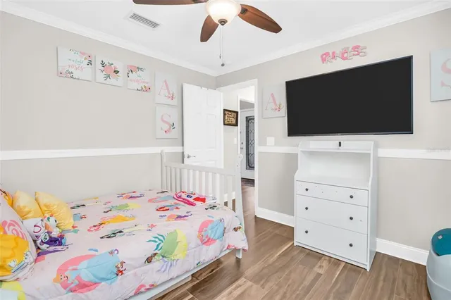 a bedroom with a bed and a flat tv screen on dresser