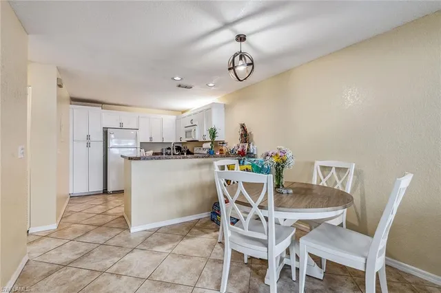 a dining room with stainless steel appliances kitchen island granite countertop a table chairs and a refrigerator