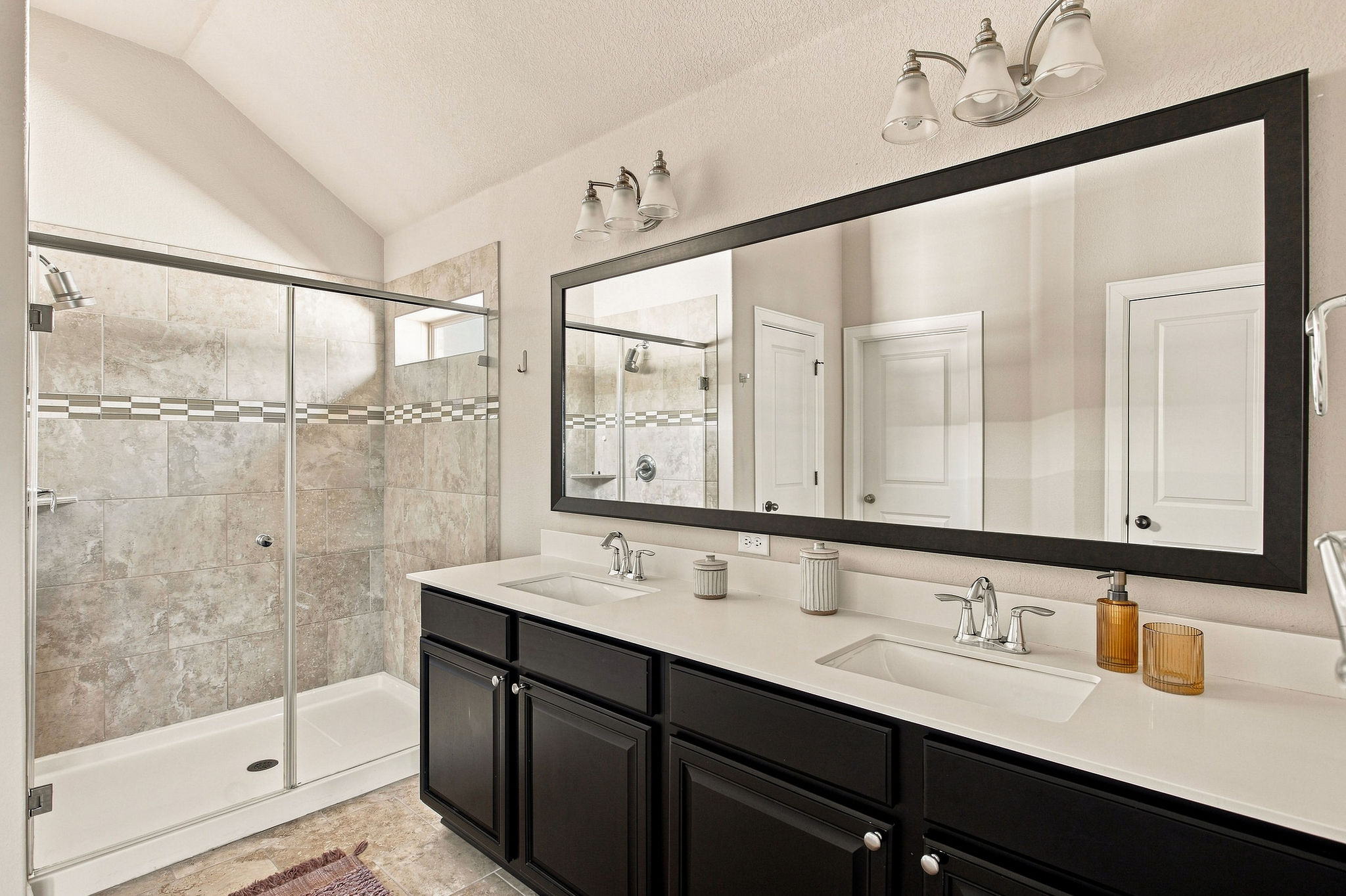 Soaring vaulted ceilings elevate this modern bathroom featuring a spacious double vanity and glass-enclosed shower.