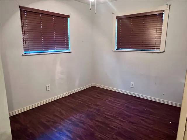 a view of an empty room with wooden floor and a painting