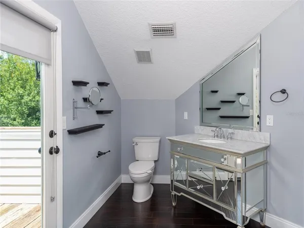 a bathroom with a granite countertop toilet a sink and a large mirror