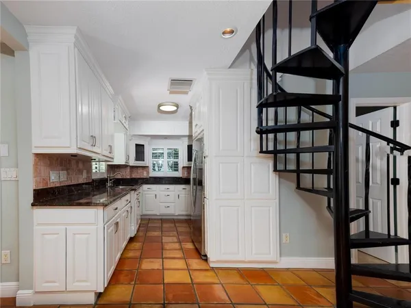 a kitchen with granite countertop a stove top oven a sink a counter space and cabinets