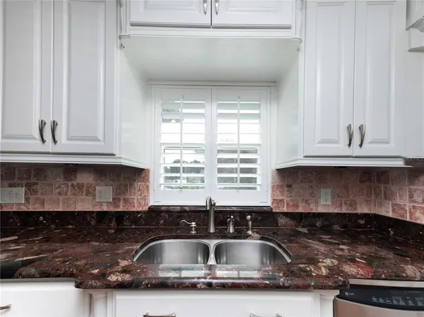 a kitchen with granite countertop white cabinets and sink