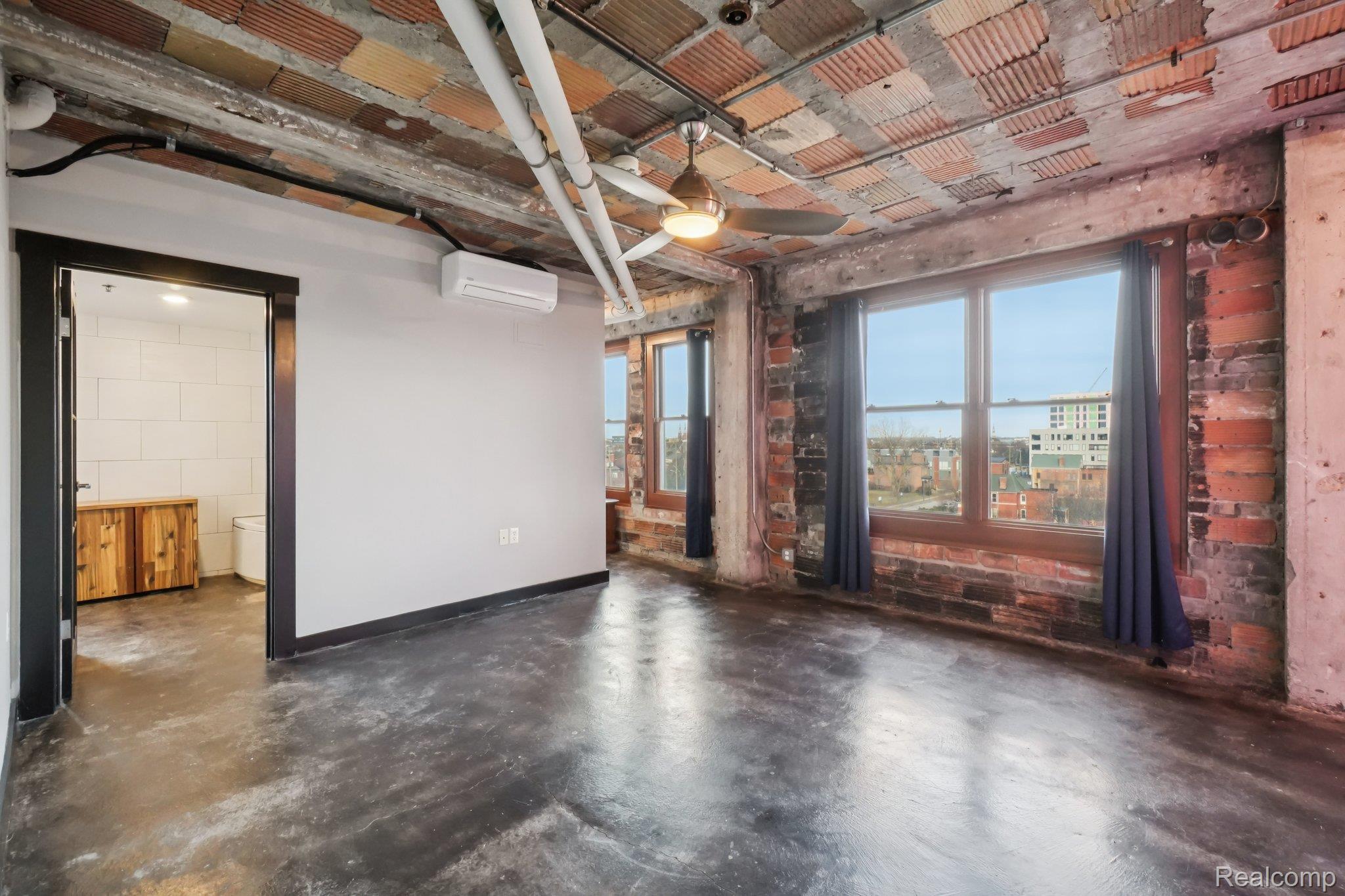 2915 John R Street Detroit, MI 48201 - Photo 7 of 30 Unfurnished room featuring concrete floors, an AC wall unit, and brick wall