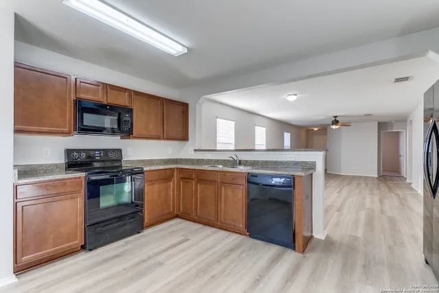 a kitchen with stainless steel appliances granite countertop a stove cabinets and a wooden floor