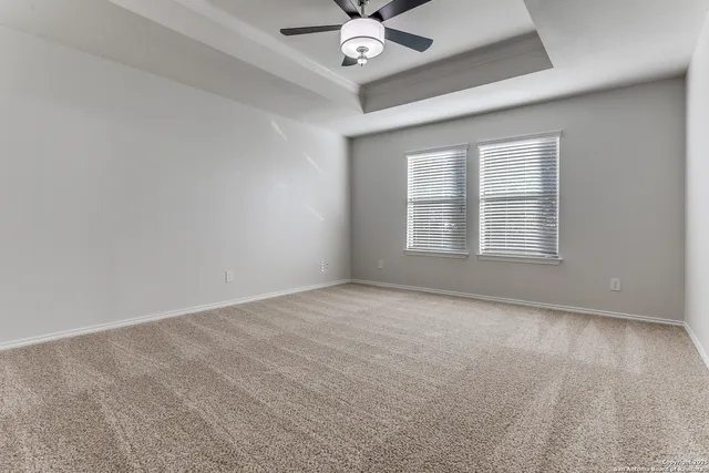 an empty room with windows and ceiling fan