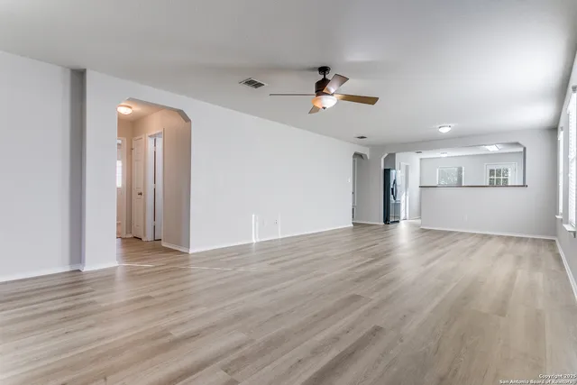 a view of empty room with wooden floor and ceiling fan