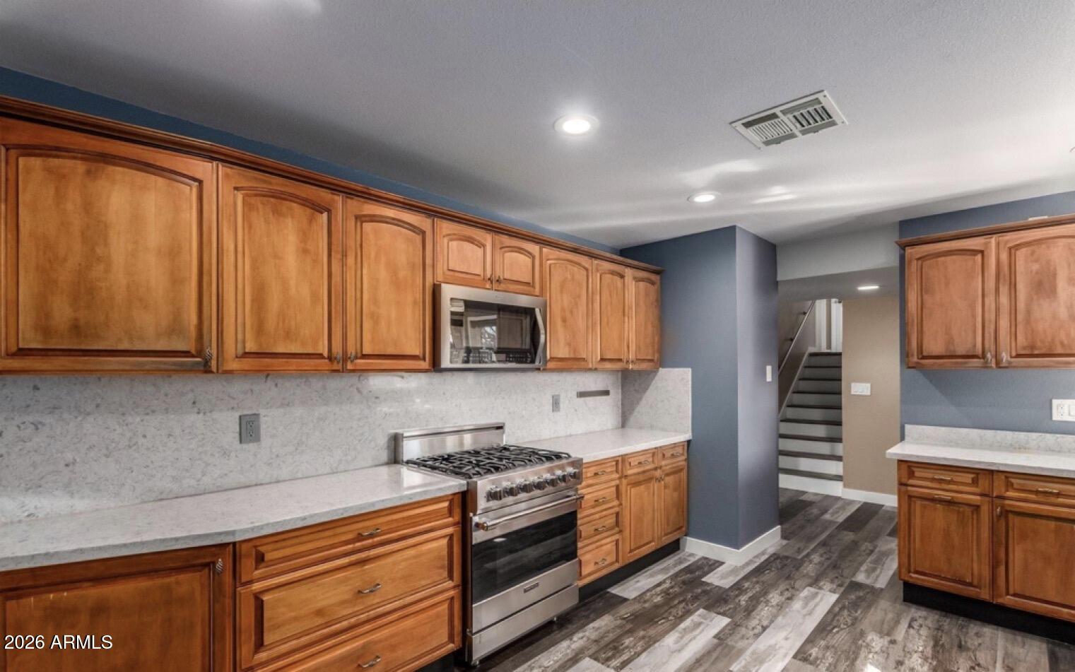 5130 West Redfield Road Glendale, AZ 85306 - Photo 6 of 35 a kitchen with stainless steel appliances granite countertop wooden cabinets a sink and a stove