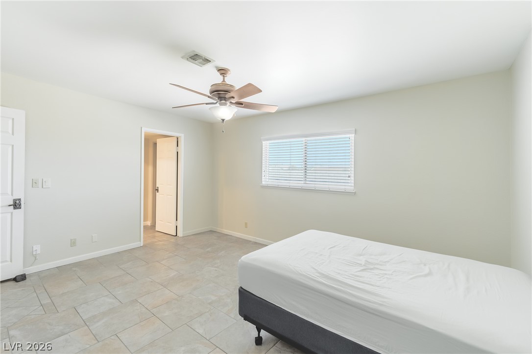 6820 Patayan Road Las Vegas, NV 89146 - Photo 16 of 31 A comfortable bedroom with cool tile flooring, a window providing natural light, and a convenient ceiling fan.