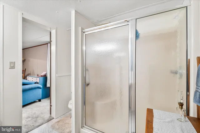 a bathroom with a glass shower door and a table