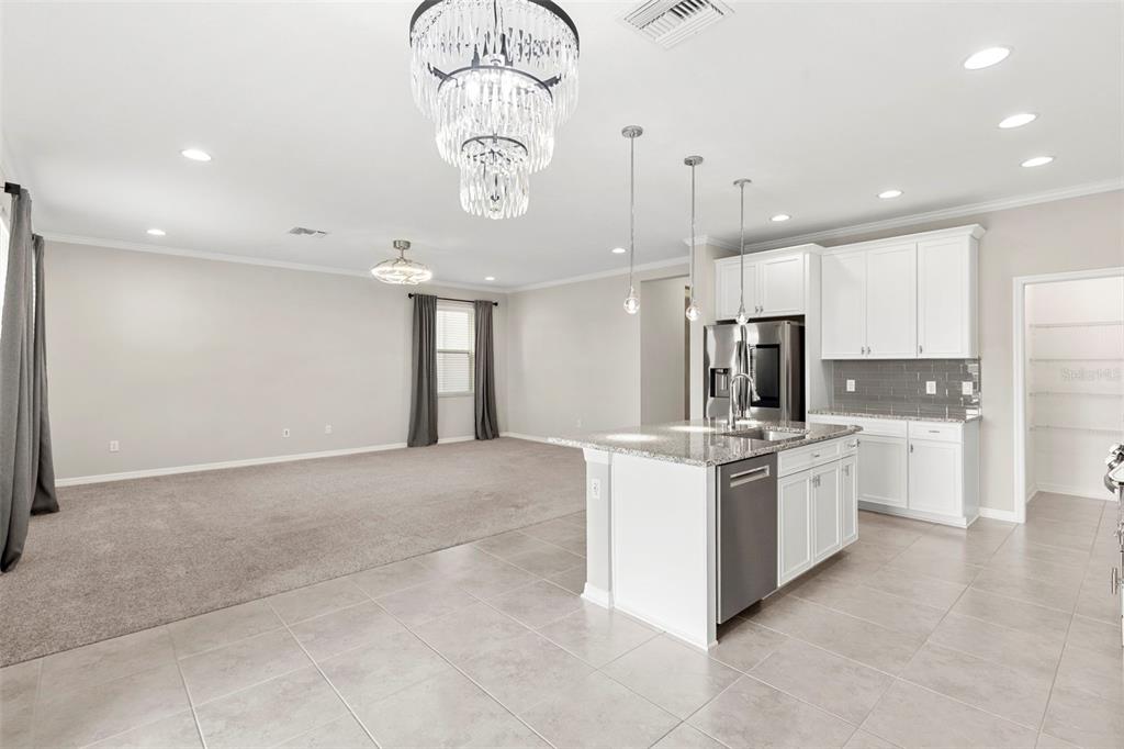 7537 Pool Compass Loop Wesley Chapel, FL 33545 - Photo 14 of 50 a kitchen with stainless steel appliances a refrigerator a stove a sink and a chandelier