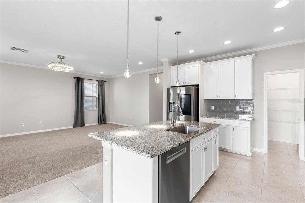7537 Pool Compass Loop Wesley Chapel, FL 33545 - Photo 16 of 50 a kitchen with kitchen island a refrigerator a sink and a stove