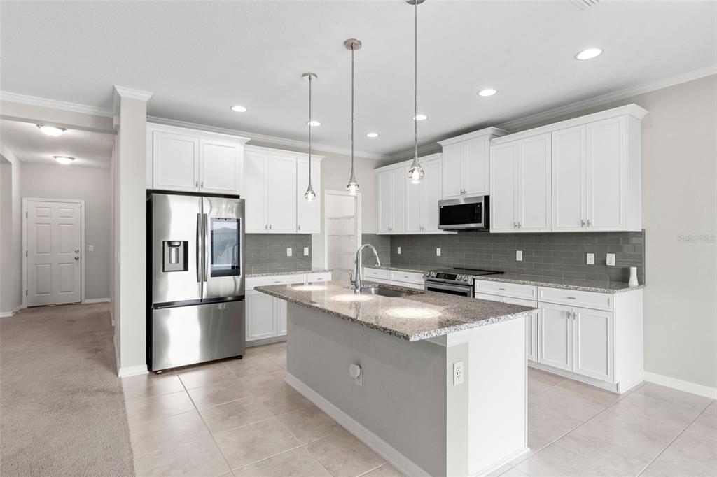 7537 Pool Compass Loop Wesley Chapel, FL 33545 - Photo 17 of 50 a kitchen with stainless steel appliances granite countertop a refrigerator a stove a sink and a microwave