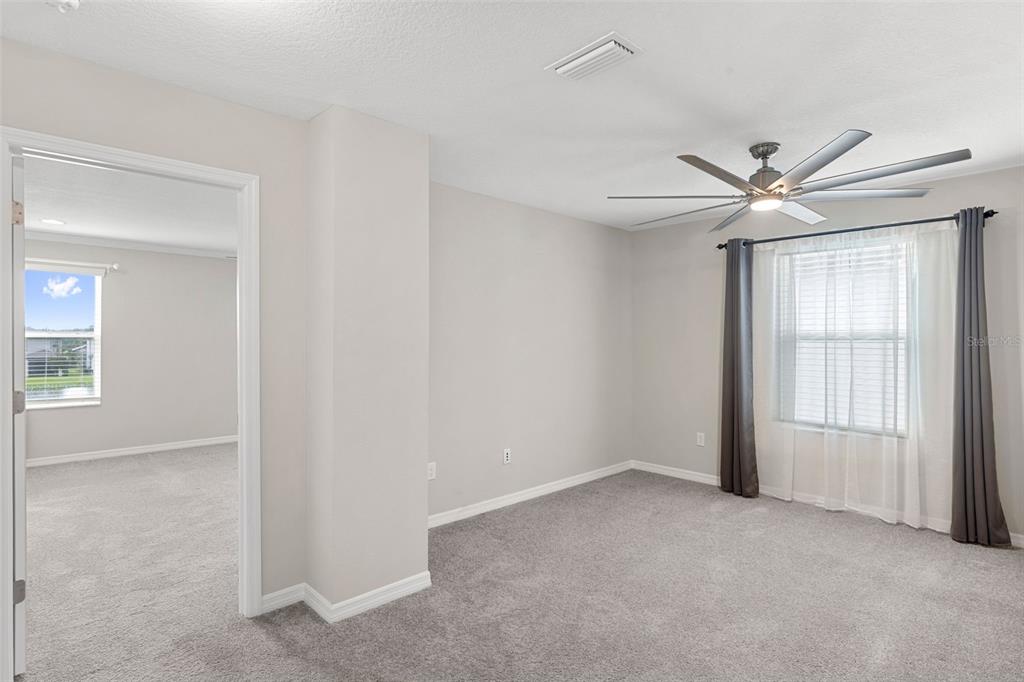 7537 Pool Compass Loop Wesley Chapel, FL 33545 - Photo 30 of 50 an empty room with windows and ceiling fan