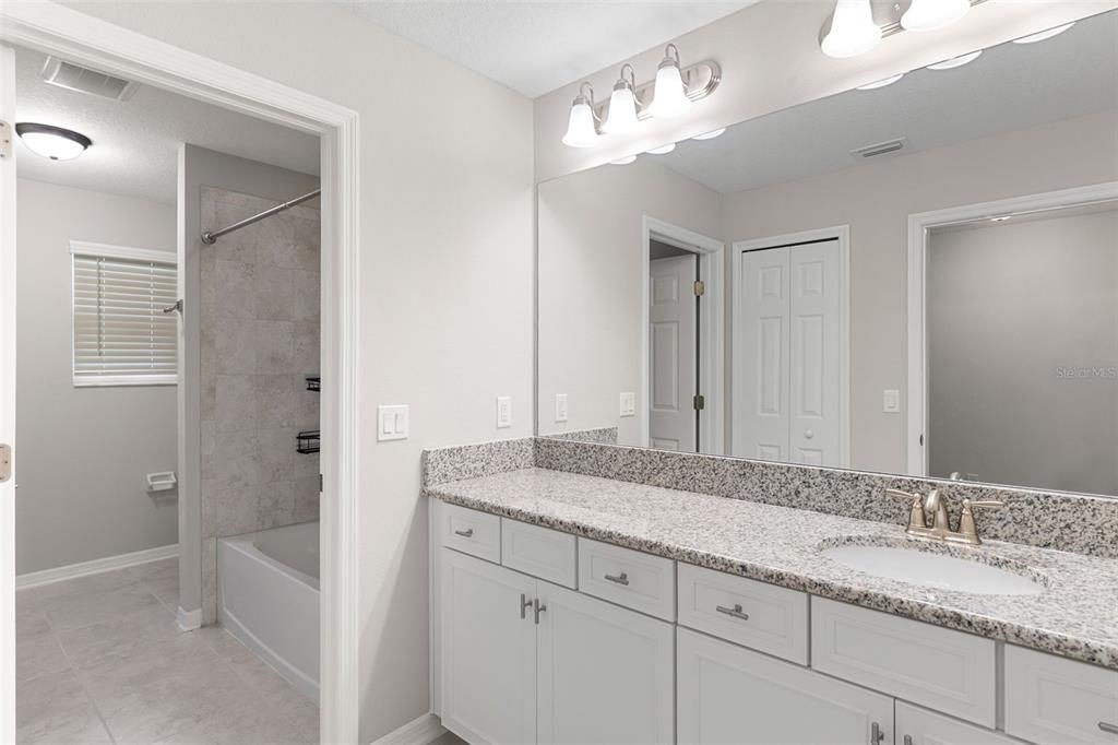 7537 Pool Compass Loop Wesley Chapel, FL 33545 - Photo 38 of 50 a bathroom with a granite countertop sink two mirror and a shower