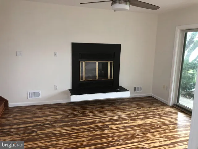 a view of a livingroom with wooden floor and a fireplace