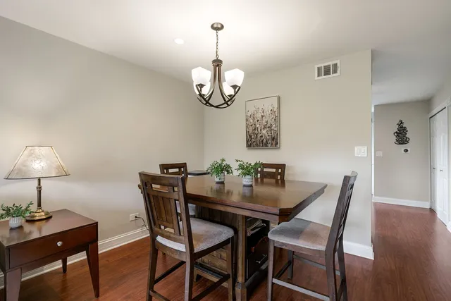a dining room with wooden floor a chandelier a wooden table and chairs