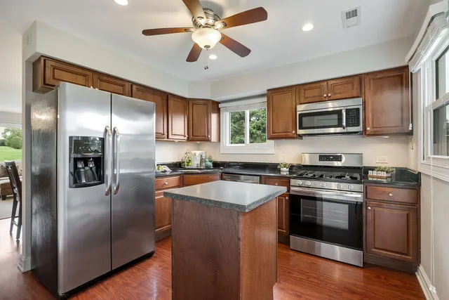a kitchen with stainless steel appliances granite countertop a stove top oven a refrigerator and a sink