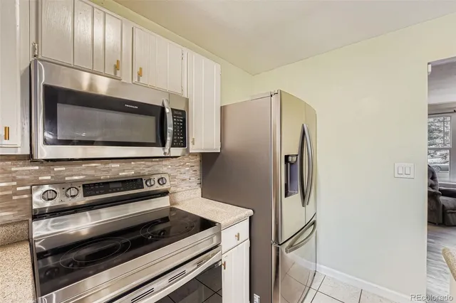 a kitchen with granite countertop a refrigerator and a microwave