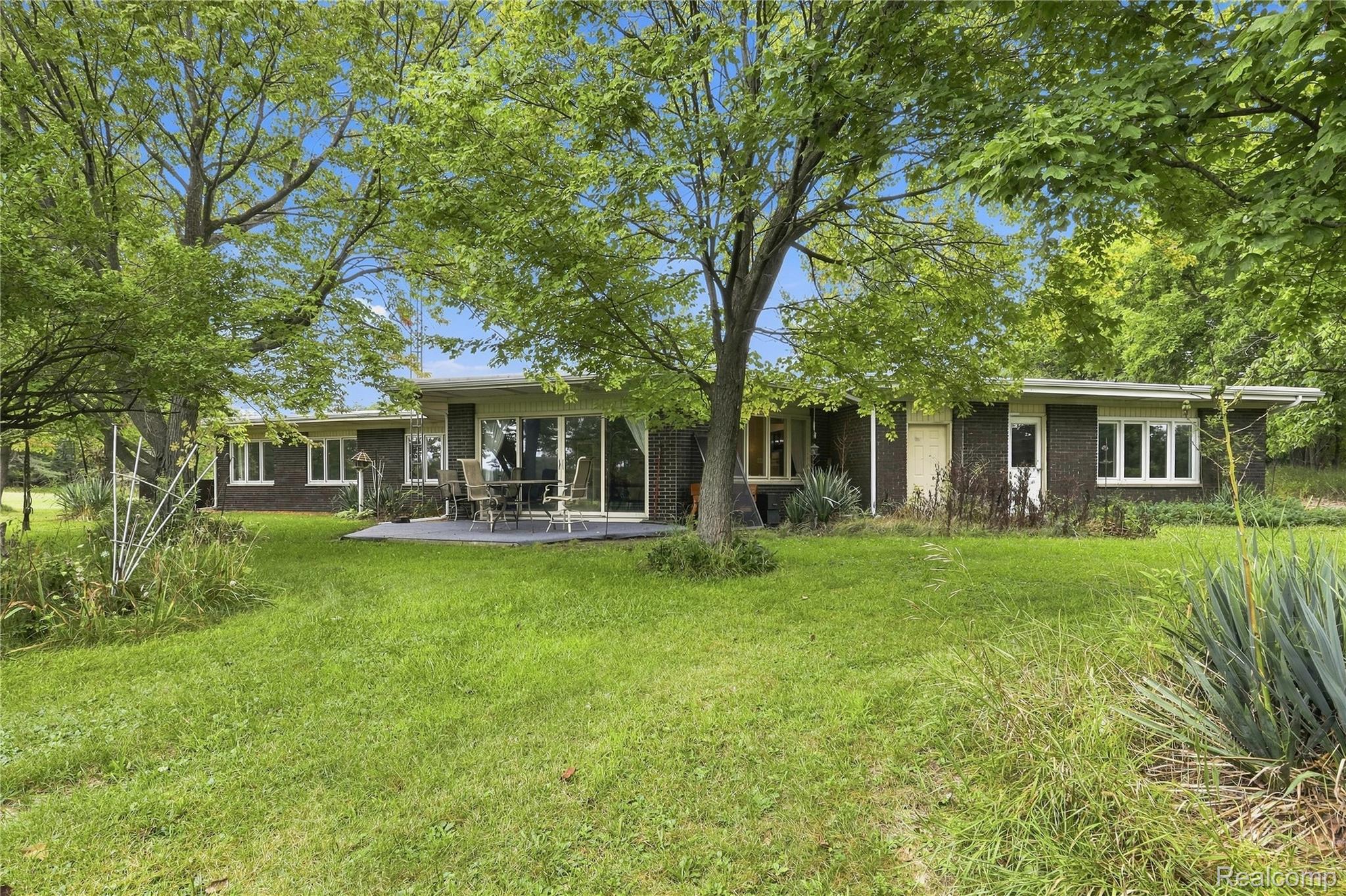 7386 Dean Road Fenton, MI 48430 - Photo 57 of 64 Dark brick exterior with multiple windows, sliding glass patio doors, and a patio area
