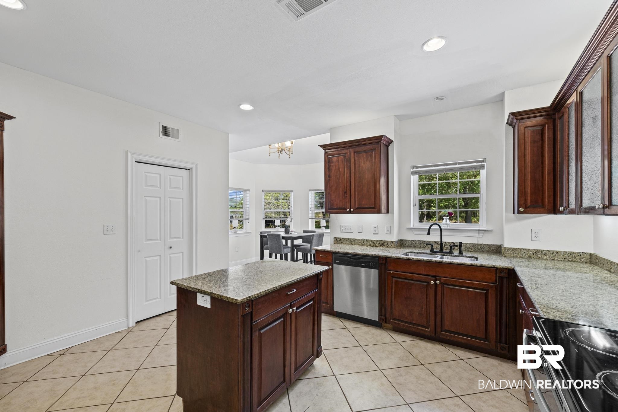 32875 Faircloth Road Lillian, AL 36549 - Photo 22 of 85 Kitchen with a kitchen island, light tile patterned floors, stainless steel dishwasher, light stone counters, and suspended lighting