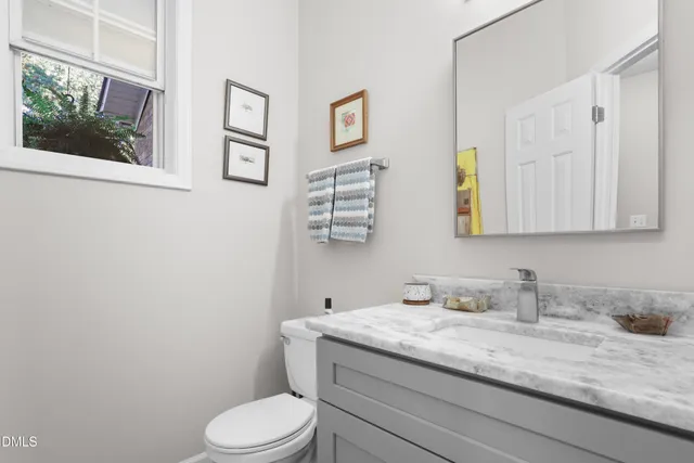 a bathroom with a granite countertop toilet sink and mirror