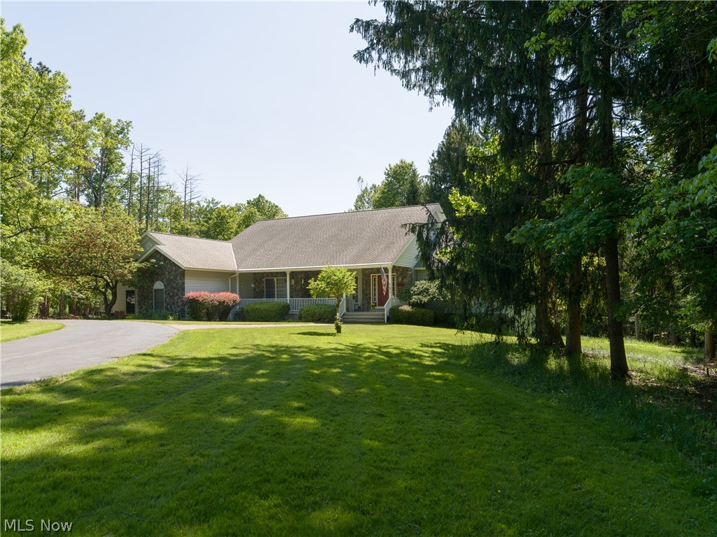 Ranch-style residence featuring a stone and siding exterior, a covered front porch, and a paved driveway