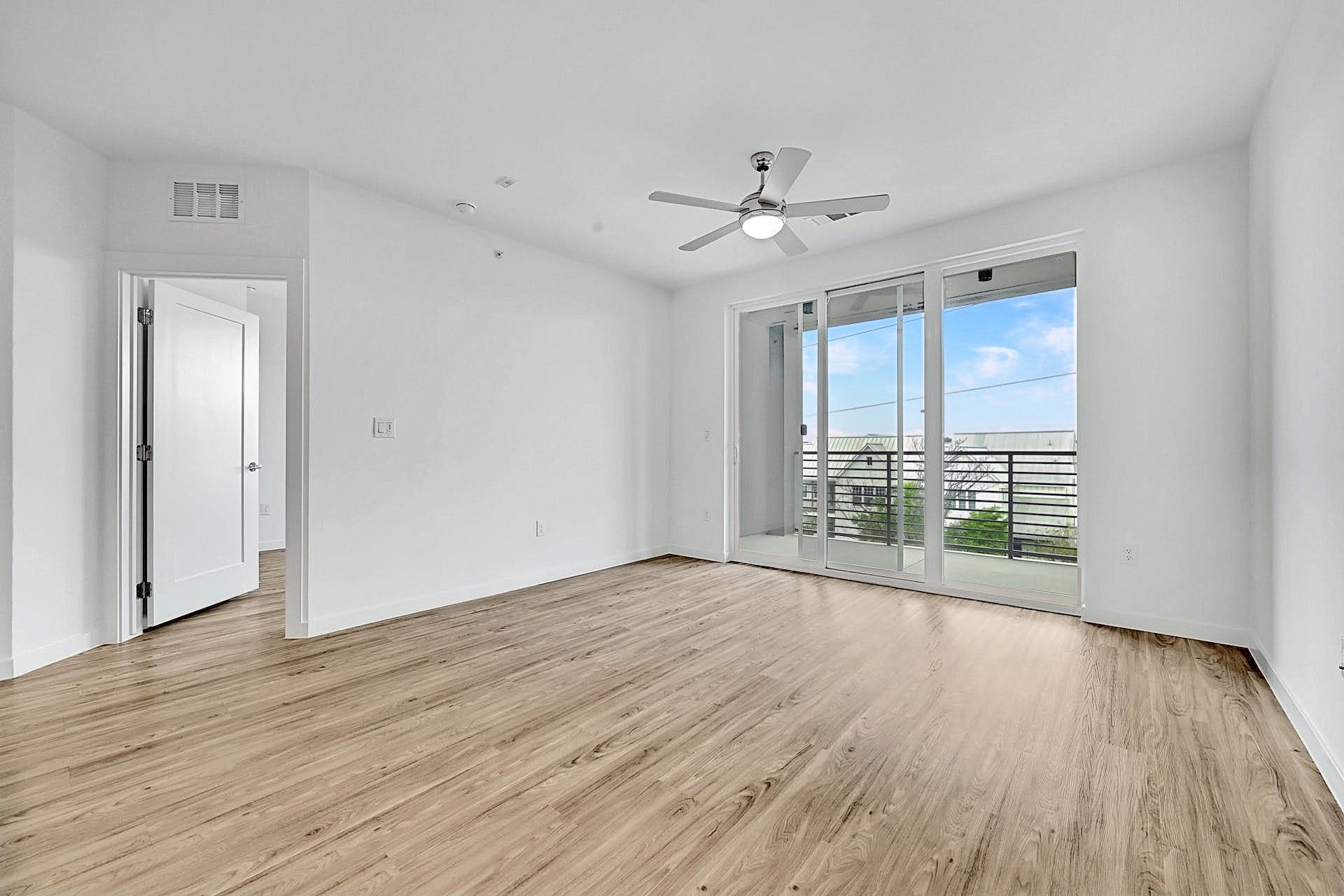 4801 Springdale Road, Unit 1301 Austin, TX 78723 - Photo 17 of 39 Natural light pours into this room, highlighting the clean wood flooring and inviting balcony access.