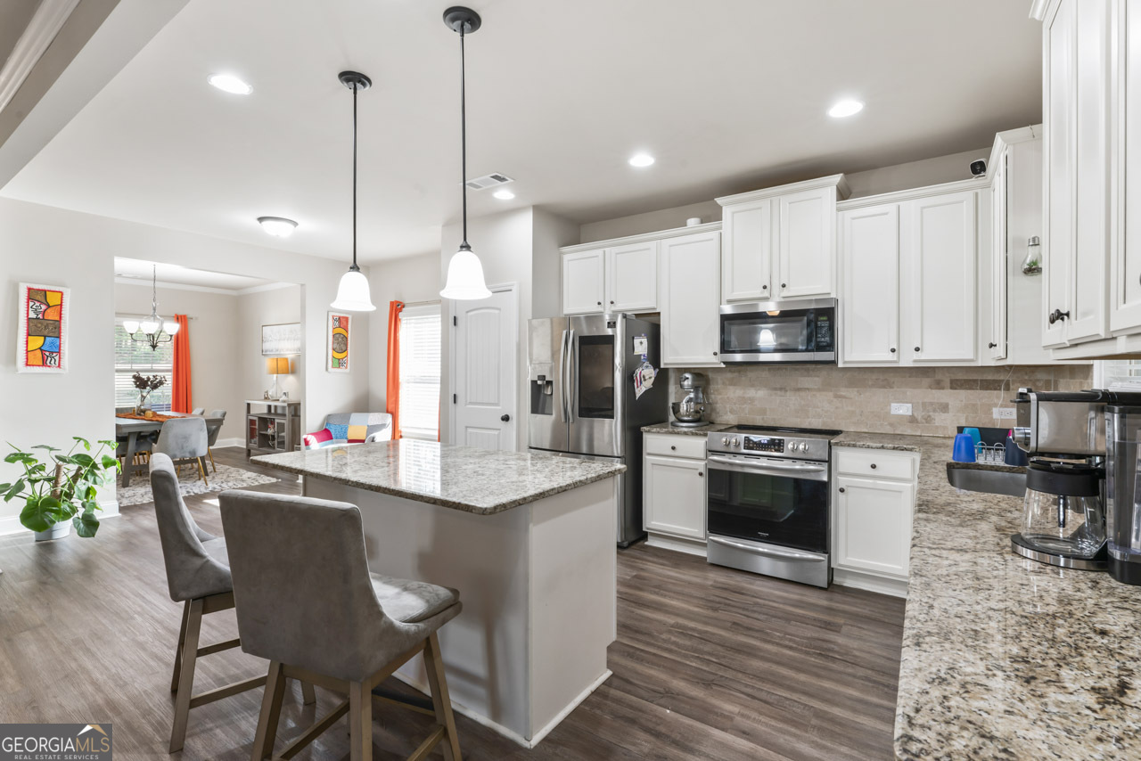 643 Patillo Road Stockbridge, GA 30281 - Photo 13 of 30 a kitchen with stainless steel appliances kitchen island granite countertop a stove a sink a refrigerator a stove a dining table and chairs with wooden floor