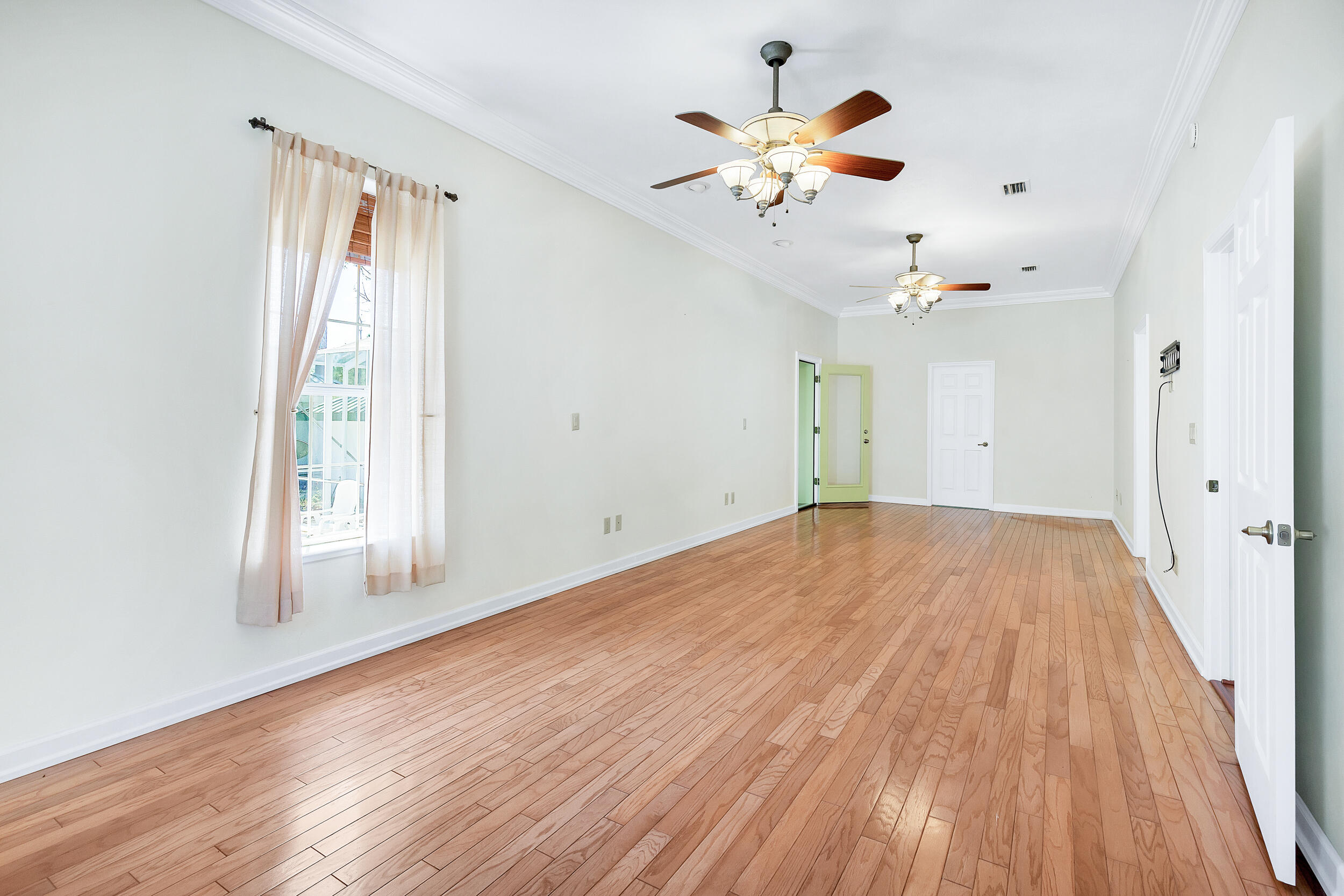 389 Churchill Bayou Road Santa Rosa Beach, FL 32459 - Photo 13 of 38 an empty room with wooden floor chandelier fan and windows