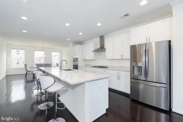 a kitchen with a refrigerator a sink dishwasher and white cabinets with wooden floor
