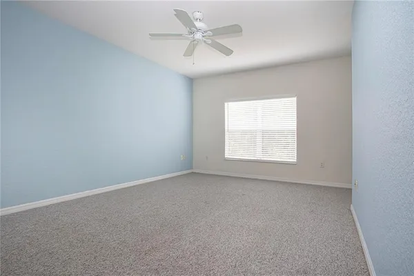 an empty room with a window and a ceiling fan