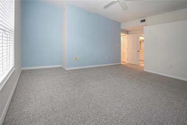 an empty room with an entryway and chandelier fan