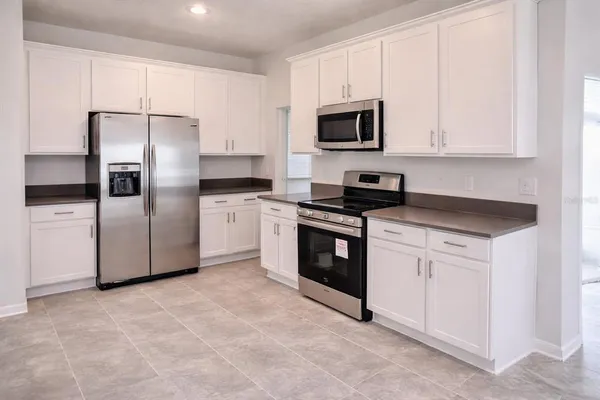 a kitchen with granite countertop white cabinets and stainless steel appliances