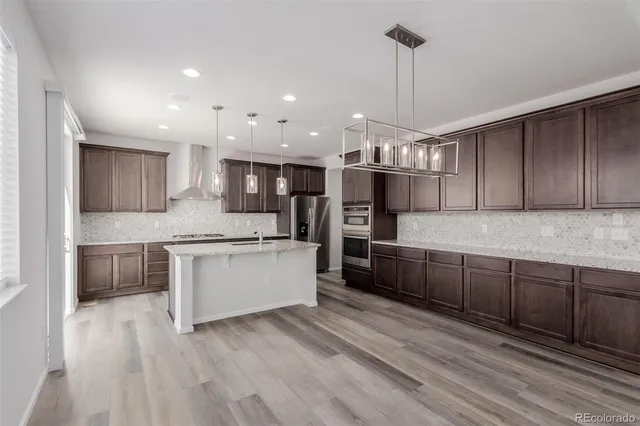 a large kitchen with granite countertop a large counter top a sink stainless steel appliances and cabinets