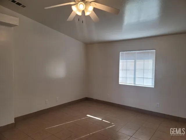 an empty room with a chandelier fan and windows