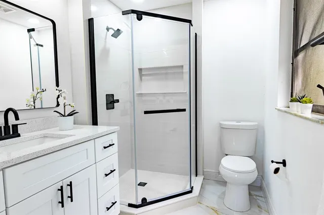 a bathroom with a granite countertop sink toilet a mirror a vanity and shower